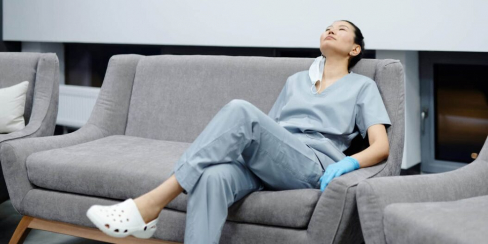 Photo of a tired healthcare professional resting on a grey couch