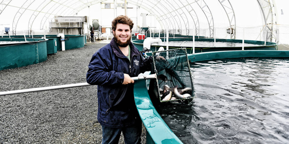 A man stands smiling in front of a pool in the land-based fish farm.