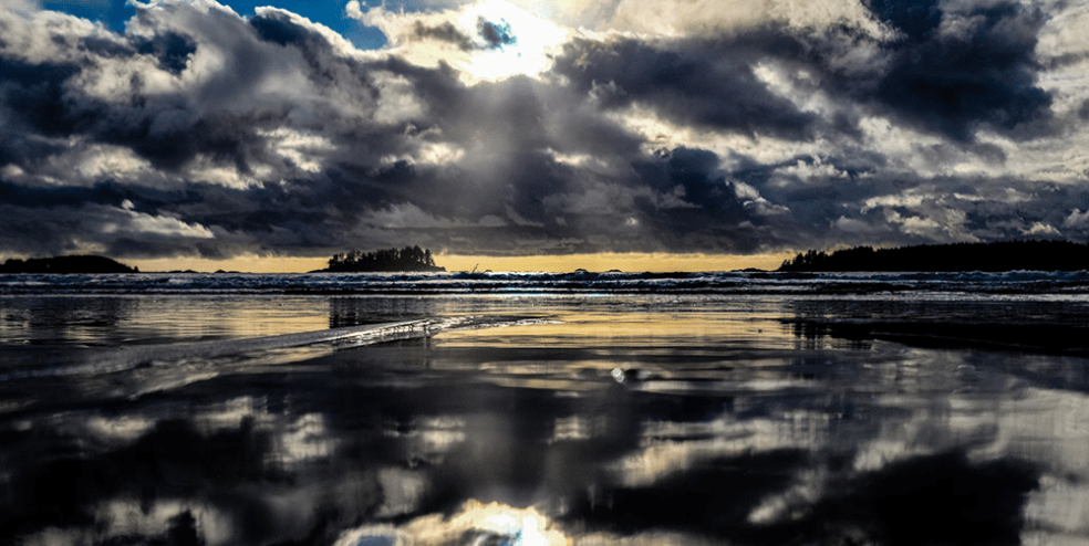 Tofino BC beach at sunset with dark clouds.