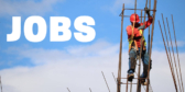 A construction worker stands on rebar above a building with nothing but a blue sky and clouds for a background.