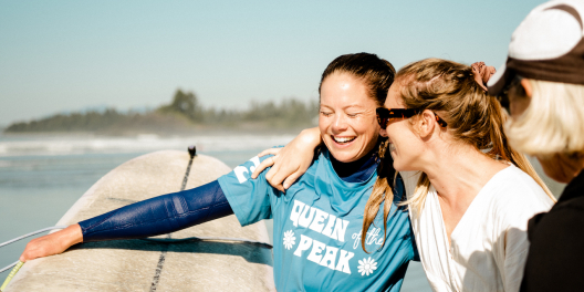 Women surfers celebrate on the beach on a sunny day.