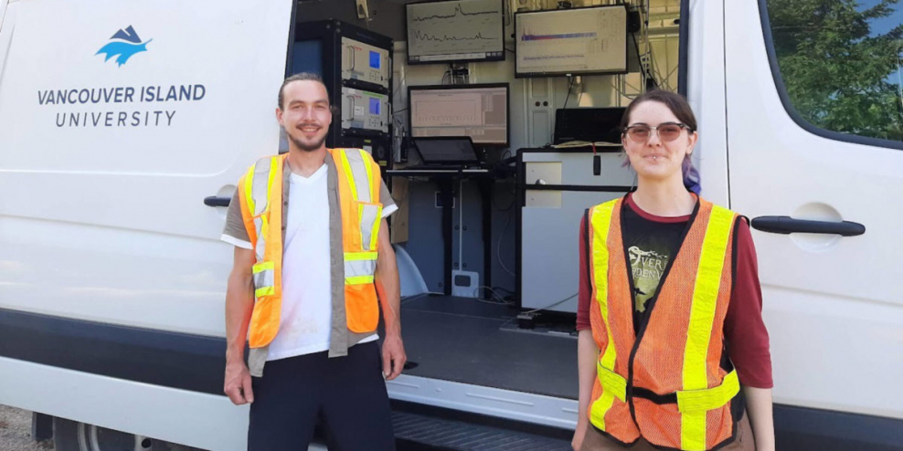 Researchers from VIU stand in front of their study van wearing bright orange safety vests.